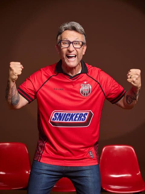 Craque Neto vestindo o manto vermelho 2026 do Brasil de Pelotas, edição Snickers, da Kelme